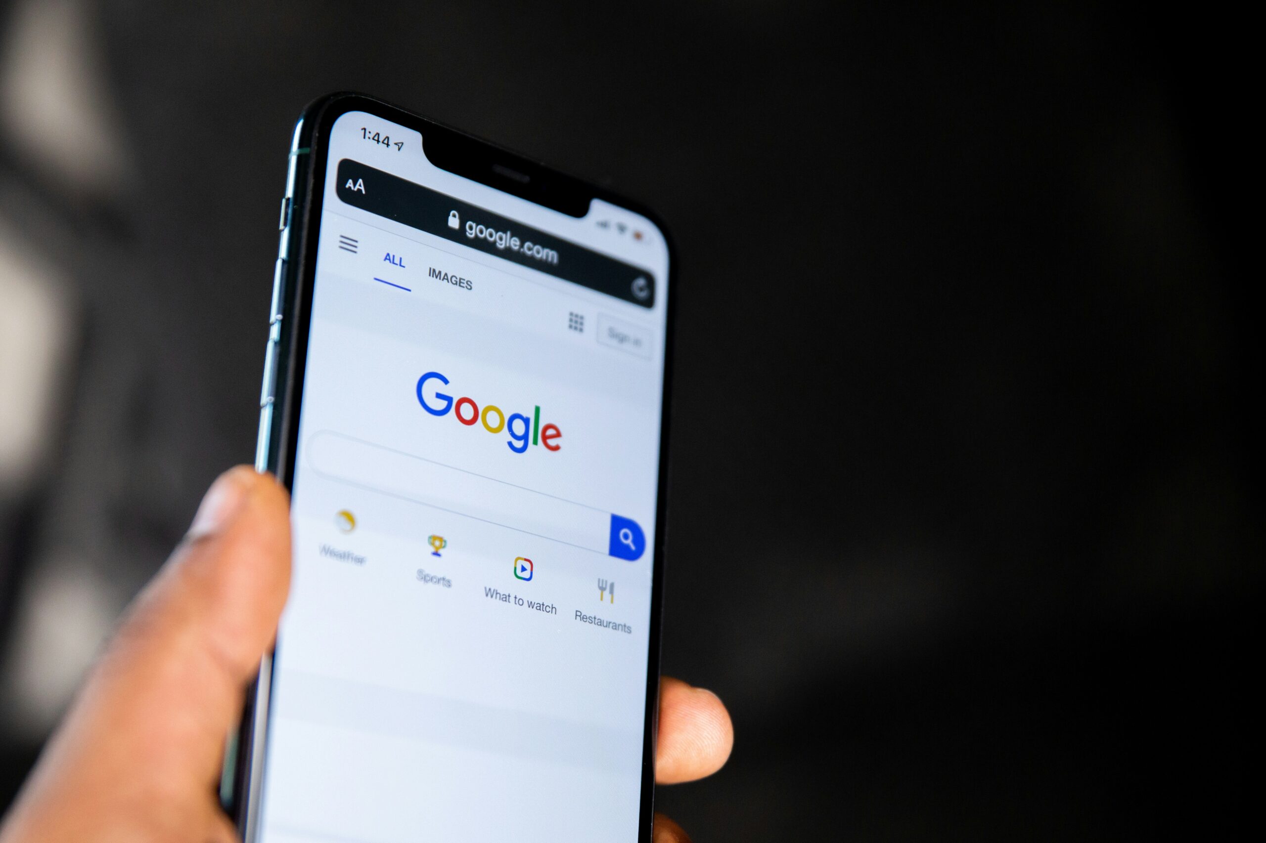 Person holding a mobile phone with Google on the screen